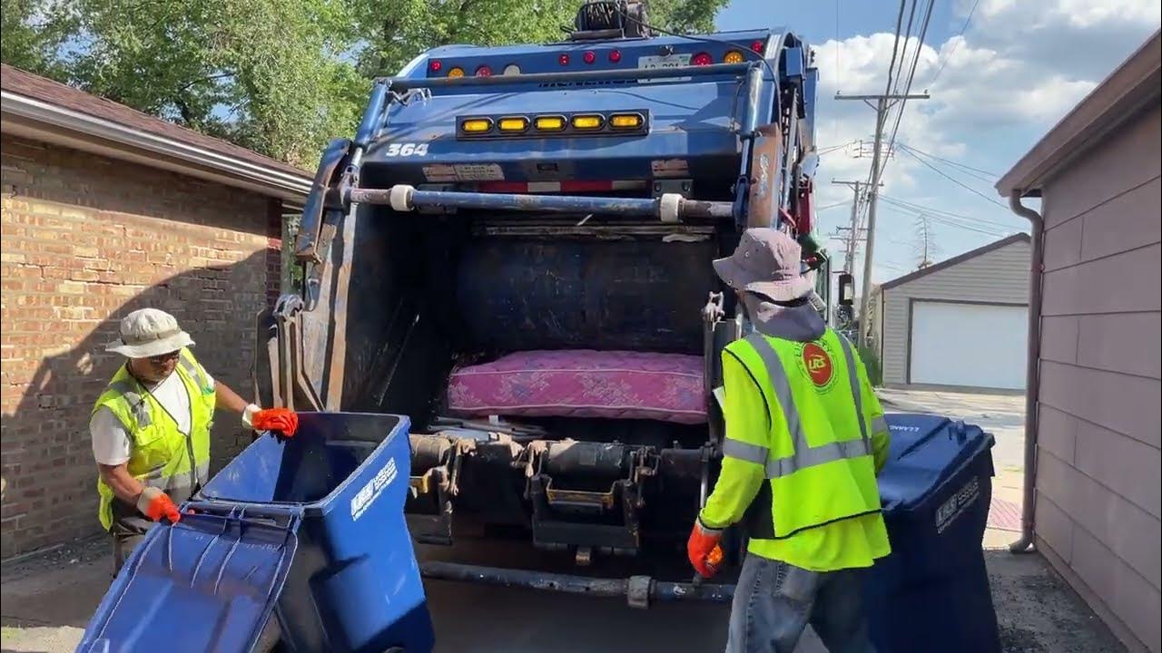 a garbage truck with two men picking up trash